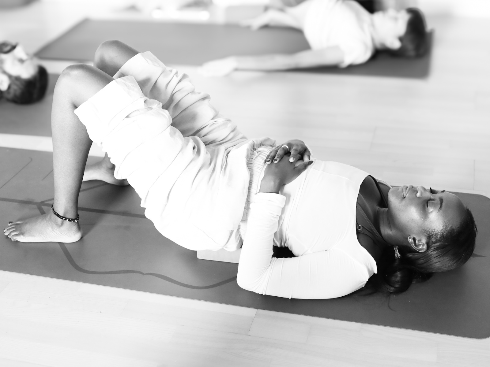 A student practicing a restorative yoga pose while resting on a supportive foam block