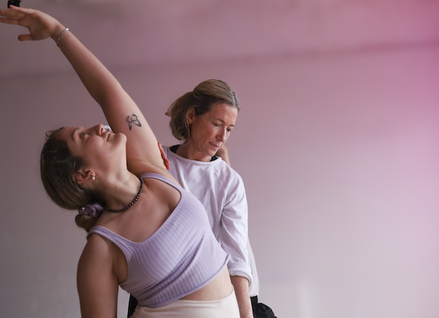 Trainee practicing yoga assists on yoga teacher training course