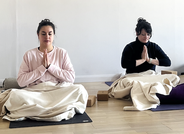 Two students in meditation at the end of a yoga class during yoga teacher training